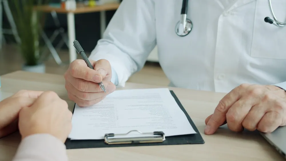 Médecin complétant le dossier médical d'un patient lors d'une consultation